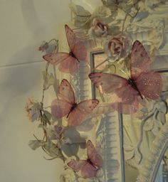 a mirror with some pink butterflies on it and flowers in front of the mirror,