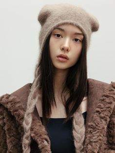 a woman with long hair wearing a brown hat and fur coat over her head,