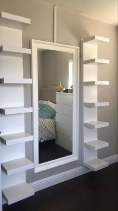 there is a mirror in the room with shelving on the wall next to it