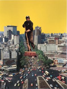 a man standing on top of a giant broom in the middle of a busy city