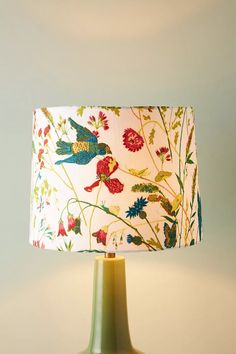 a lamp that is sitting on a table with a flowered lampshade in front of it