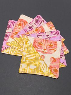 four coasters with cats on them sitting next to each other in front of a black background