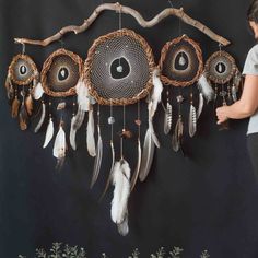 a woman standing next to a wall hanging with dream catchers