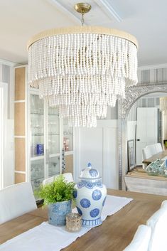 a chandelier hanging from the ceiling in a dining room with blue and white decor