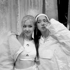 two young women standing next to each other in front of a curtained wall and posing for the camera