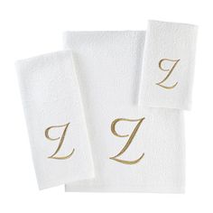 three white towels with gold letters on them