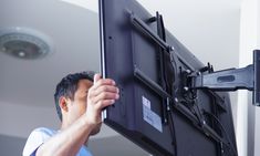 a man is holding up a large screen to take it off the ground with his hands