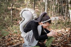 a woman kneeling down in the woods with a squirrel costume on