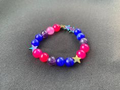 Bisexual/Biromantic pride flag star beaded gemstone bracelet. The beads are the bi flag colors (pink, purple, blue) and holographic stars. ♥ Bracelet Size: - To find the size that fits you best, you can measure the circumference around your wrist; for a comfort/loose fit, add 2cm to that measurement ♥ Handcrafted With: ✔ High-quality gemstone beads ✔ Durable stretchy cord Thank you for visiting! If you have any questions, feel free to contact me!  Instagram: @FrogsMakingToast Handmade Multicolor Star Bracelets, Multicolor Star-shaped Bracelet With Colorful Beads, Multicolor Star-shaped Beaded Bracelets For Friendship, Purple Star-shaped Bracelets For Gifts, Rainbow Star-shaped Bracelet For Gift, Purple Star-shaped Bracelet For Gift, Adjustable Star-shaped Bracelets With Colorful Beads, Adjustable Star Shaped Bracelet With Colorful Beads, Star-shaped Colorful Beaded Bracelets As Gift