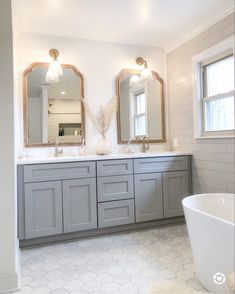 a bathroom with double sinks and two mirrors on the wall next to a bathtub