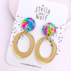 a pair of gold hoop earrings with multicolored circles and polka dots on them