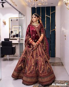 a woman in a red and gold bridal gown posing for the camera with her hands on her hips