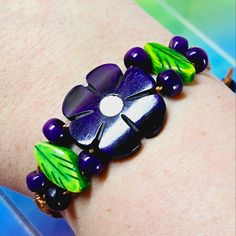 a close up of a person's arm wearing a bracelet with flowers on it