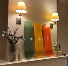 three skateboards are lined up against the wall next to a vase with flowers in it