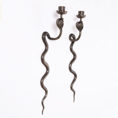 two candle holders made out of metal and decorated with snake's tail design, on white background