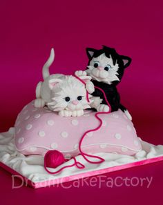 two cats sitting on top of a cake