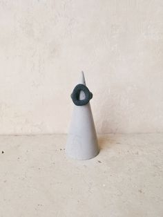 a small white cone with a black ring on it's end sitting in front of a wall