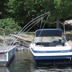 a blue and white boat tied to a dock in the water with trees behind it