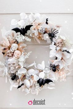 a white wreath with flowers and bats on it is hanging from the side of a door