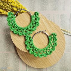 green crochet hoop earrings with tassels on top of a piece of wood