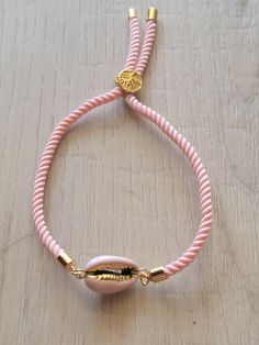 Genuine cowrie shell in pink enamel with gold accents on a pink silk cord adjustable bracelet.  Adjusts up to an 8" wrist. Pink Braided Bracelet With Adjustable Cord As Gift, Pink Adjustable Cord Braided Bracelet, Pink Adjustable Friendship Bracelets, Pink Adjustable Bracelet Jewelry, Pink Friendship Bracelets With Adjustable Cord, Pink Resizable Braided Bracelet, Adjustable Pink Resizable Braided Bracelets, Adjustable Pink Braided Bracelets For Beach, Adjustable Resizable Pink Braided Bracelets