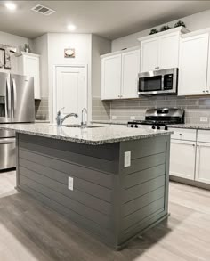 a large kitchen with white cabinets and stainless steel appliances in the center, along with granite counter tops