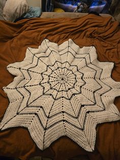 a white crocheted doily sitting on top of a bed next to a pillow