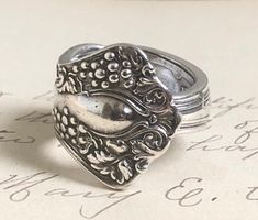 "This pretty ring is made from the pattern \"VINTAGE\" It is a pretty pattern with a grape motif in the Art Deco style.  It was made from the handle of a single spoon. It was manufactured in 1904.  It is a size 6.5 but can be adjusted up or down a size or two at your request. It measures 3/4\" at its widest point. Much care has gone into the process for comfort.  Carefully hand selected from treasured flatware from the past and repurposed into beautiful art to adorn you today! Any questions, please feel free to contact me before, during or after a sale. I am here to help you find a cherished treasure that you will love a lifetime ❤️🌿" Handmade Antique Silver Vintage Rings, Handmade Vintage Antique Silver Rings, Vintage Engraved Ring With Antique Finish For Anniversary, Vintage Stamped Engraved Ring, Vintage Adjustable Nickel-free Engraved Ring, Vintage Adjustable Engraved Nickel-free Ring, Adjustable Vintage Engraved Nickel-free Ring, Adjustable Nickel-free Vintage Engraved Ring, Vintage Antique Silver Engraved Ring For Gift