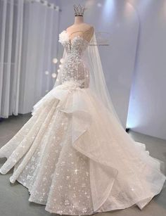 a wedding dress on display in front of a white wall with lights and curtains behind it