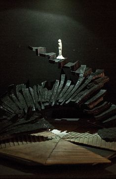 a person standing on top of a pile of wooden blocks in the dark with a light shining on them