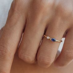 a woman's hand wearing a gold ring with an oval blue stone on it