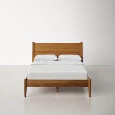 a wooden bed with white sheets and pillows