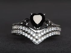 a heart shaped black and white diamond ring on top of two stacking rings with diamonds