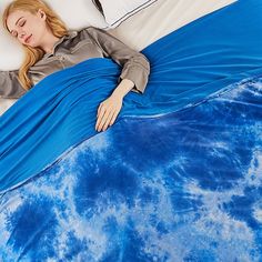 a woman laying on top of a blue and white bed