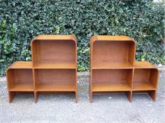 three wooden shelves sitting next to each other in front of a green hedge covered wall