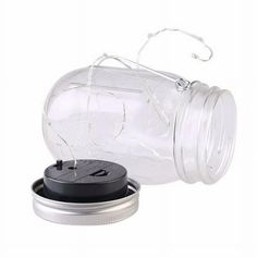 a glass jar with a black lid and an empty plastic container on the bottom that is open