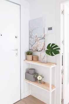 a white room with a wooden shelf and plants on it