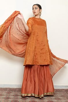 Rust kurta with embroidered floral and half moon motifs. Comes with an inner, matching gharara and chanderi silk dupatta.
Components: 4
Pattern: Embroidered
Type Of Work: Thread, Sequin
Neckline: Round
Sleeve Type: Three quarter
Fabric: Kurta: Chanderi Tissue, Gharara: Cotton Silk, Dupatta: Chanderi Silk, Lining: Cotton
Color: Orange
Other Details: 
Straight silhouette
Kurta side gathers
Occasion: Sangeet,Mehendi and Haldi - Aza Fashions Tissue Kurta Designs Women, Half Moon Mehendi Design, Ethnic Kurta Designs Women, Tissue Fabric Dress Design, Chanderi Kurta Designs, Orange Indian Outfit, Plazo Outfits, A Line Kurti Designs, Sharara Design