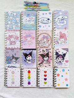 several notebooks are lined up on a white sheet with hello kitty stickers all over them