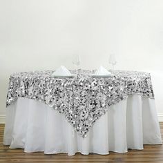 a table with silver sequins on it and two wine glasses at the top