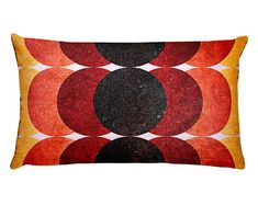 an orange, black and red pillow with circles in the middle on a white background