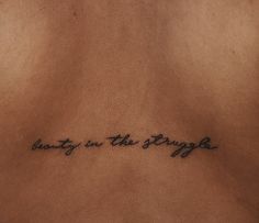 a tattoo saying beauty in the struggle on someone's back side ribcage