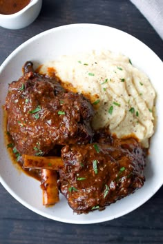 a white plate topped with meat and mashed potatoes