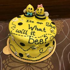 a yellow cake with black polka dots and two bees on top that says he or she what will it bee?