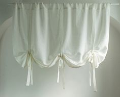 the curtains are hanging from the ceiling in front of a window with white drapes