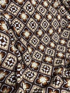 a brown and white crocheted blanket with flowers on it