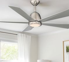 a modern ceiling fan in a bedroom with white walls and curtains on the windowsill