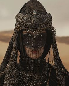 a woman in an elaborate headdress with chains and beads on her face is looking at the camera