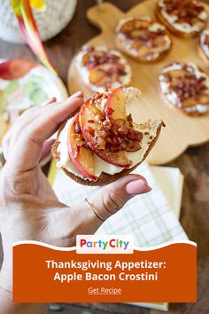 a person holding an apple bacon crostini sandwich in front of other desserts