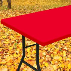 a red table sitting on top of a pile of leaves